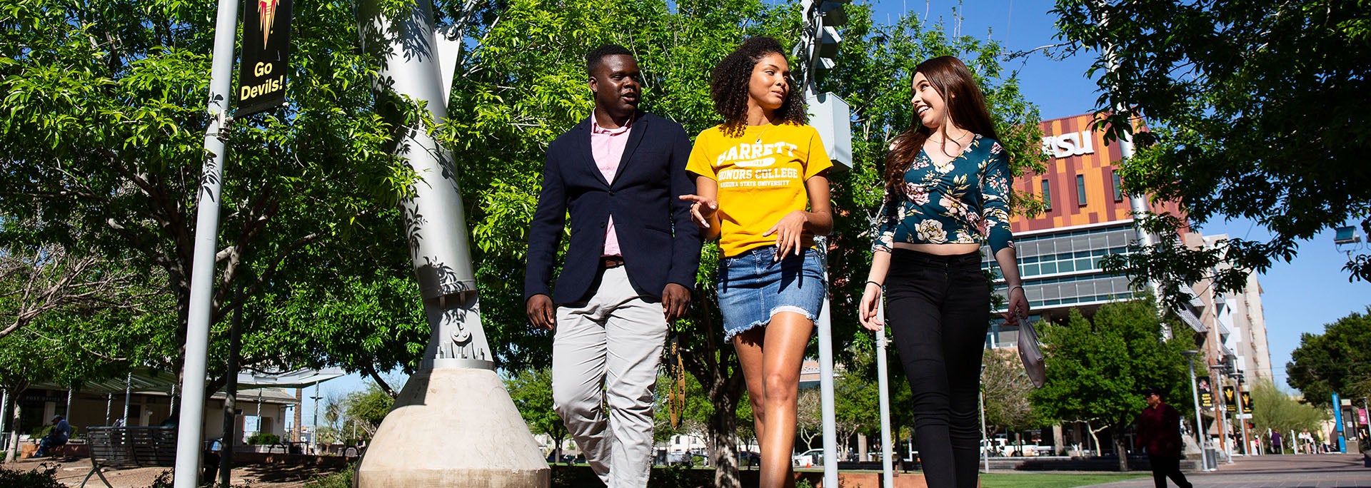 Three Barrett students walking down the Barrett Downtown campus with trees and buildings in the background