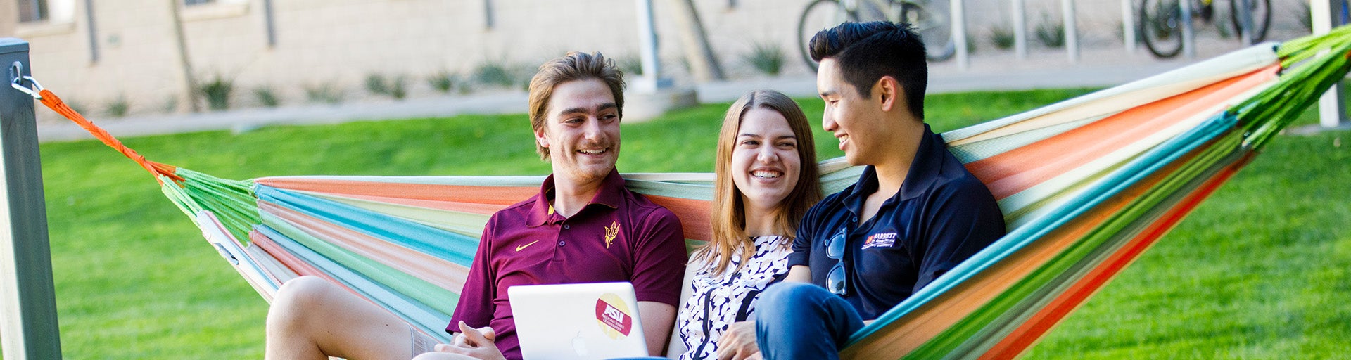 Three students sitting on a hammock outside at the Barrett Tempe Complex great court