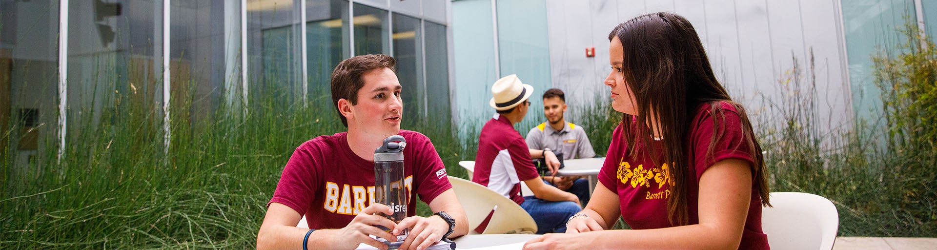 Male and female student having a conversation outside at a table