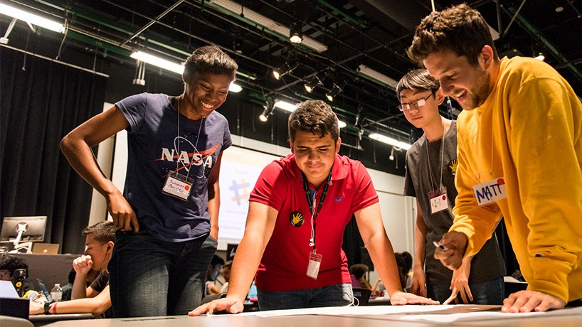 Several students working together and looking at an assignment on a large table